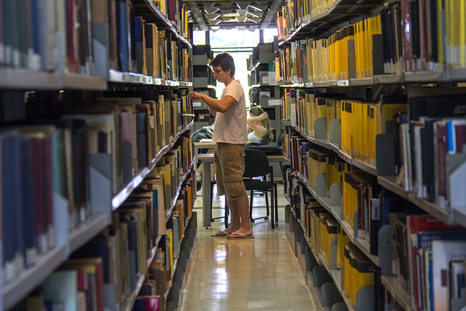 Estudante entre estantes de livros da Biblioteca Central da Universidade de Brasília