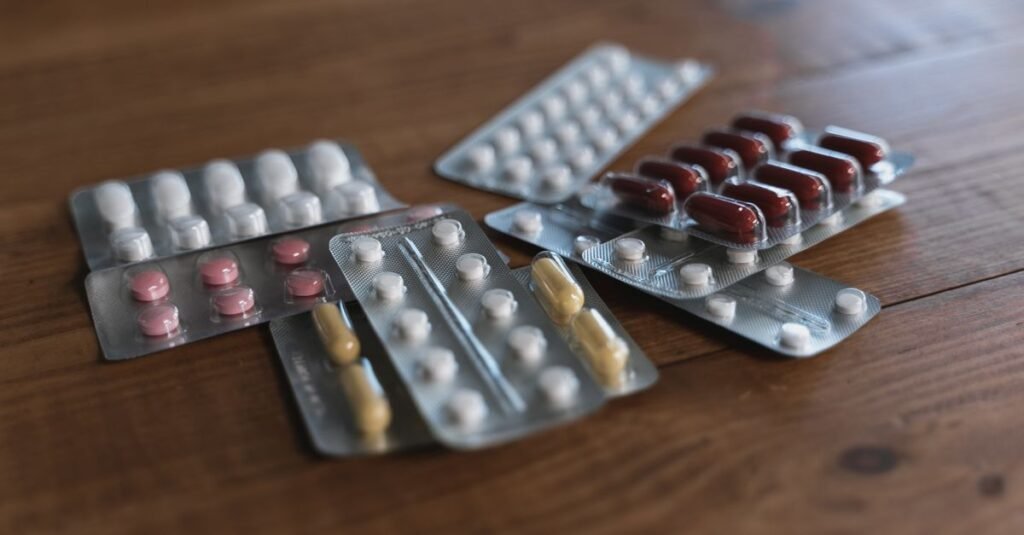 Cartelas de comprimidos e capsulas de cores variadas sobre mesa de madeira