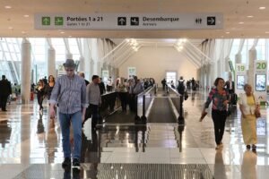 Saguao de desembarque do Aeroporto Internacional de Brasilia com passageiros e placas de sinalizacao