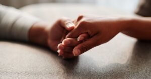Duas mãos entrelaçadas em close, gesto de apoio e acolhimento