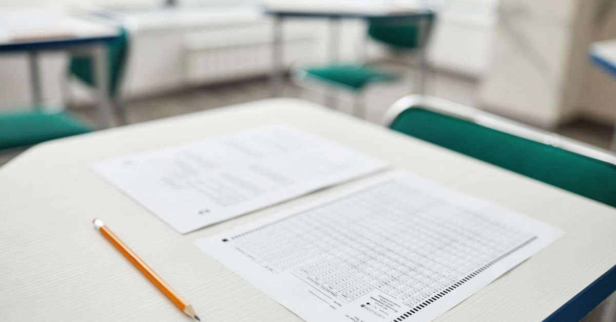 Cartão-resposta de prova escolar e lápis sobre carteira em sala de aula vazia