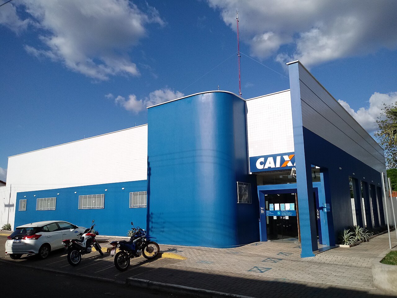 Fachada de agência da Caixa Econômica Federal, com letreiro azul e laranja