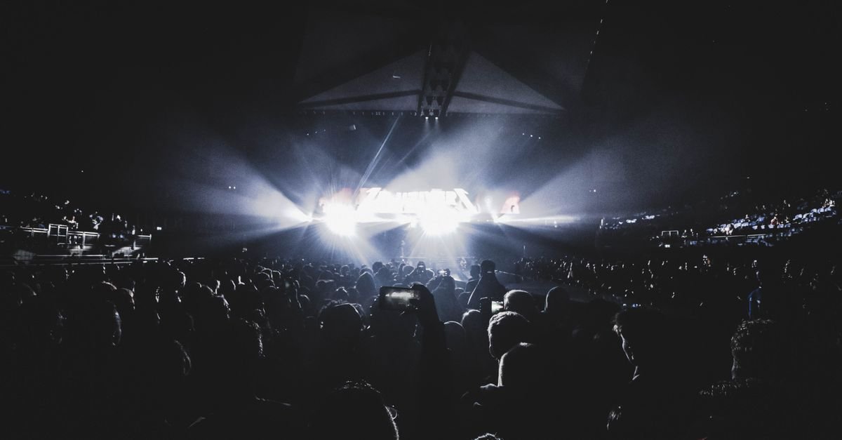 Público em show noturno com luzes de palco em arena