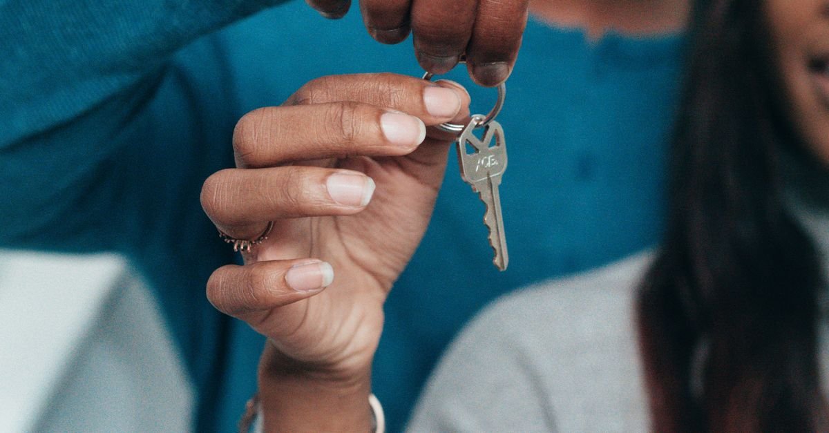 Maos de duas pessoas segurando uma chave de casa em um chaveiro