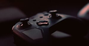 Controle de videogame sem fio fotografado de perto em ambiente escuro, com destaque para os analógicos e os botões