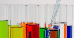 Tubos de ensaio com líquidos coloridos e pipeta de vidro em laboratório