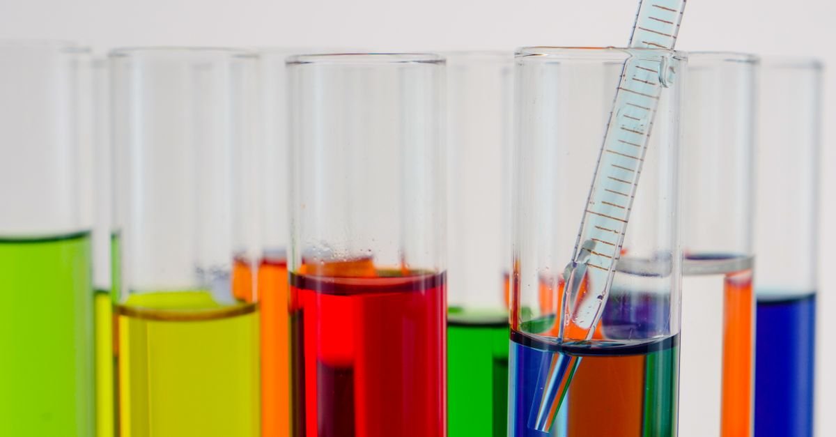 Tubos de ensaio com líquidos coloridos e pipeta de vidro em laboratório