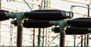 Equipamentos de alta tensão com isoladores e condutores em uma subestação de energia elétrica