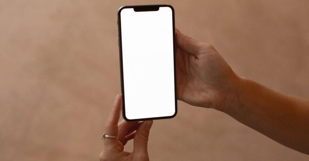 Mãos segurando um celular com a tela em branco