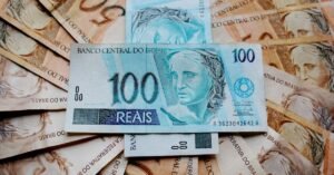 Cédulas de cem e cinquenta reais espalhadas sobre uma superfície