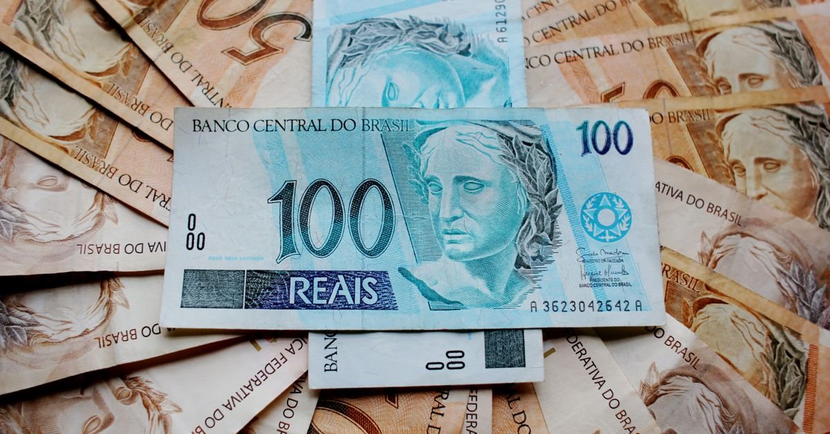Cédulas de cem e cinquenta reais espalhadas sobre uma superfície