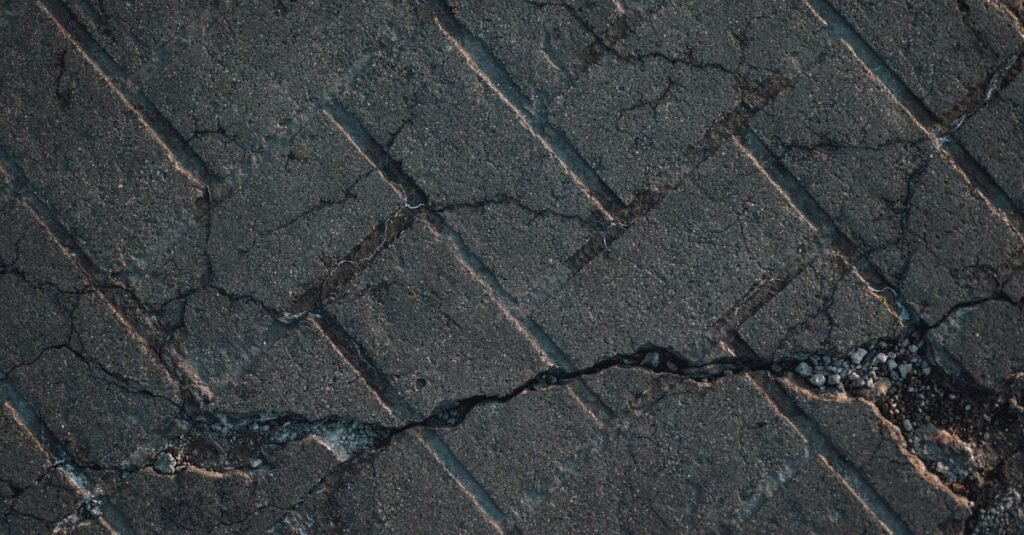 Piso de concreto com rachaduras e trechos soltos em via urbana