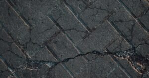 Piso de concreto com rachaduras e trechos soltos em via urbana