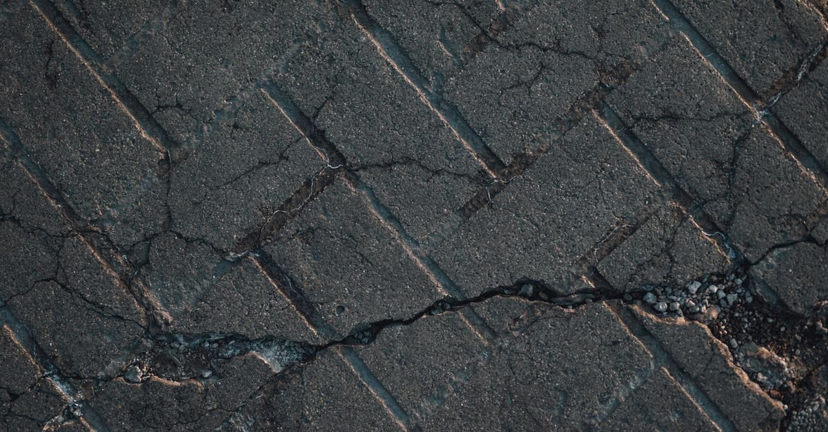 Piso de concreto com rachaduras e trechos soltos em via urbana