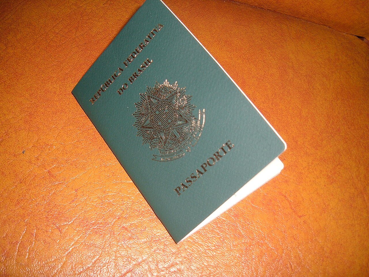 Passaporte brasileiro fechado apoiado sobre superfície de couro