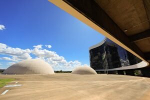 Fachada de vidro da sede do Tribunal Superior Eleitoral, em Brasília, com as cúpulas em primeiro plano