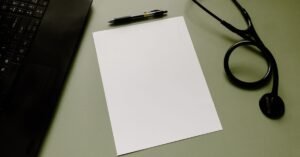 Estetoscópio, folha em branco e caneta sobre mesa de consultório