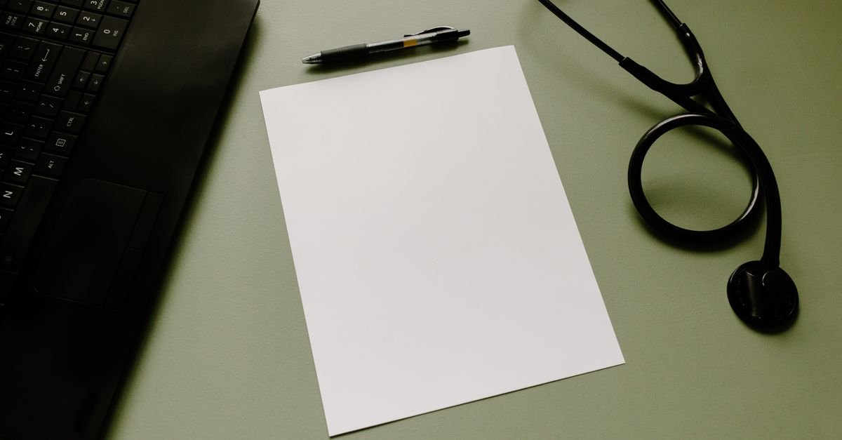 Estetoscópio, folha em branco e caneta sobre mesa de consultório