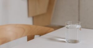 Copo de água sobre mesa branca em ambiente interno