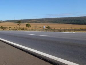 Pista da BR-020 no Distrito Federal, com faixa de rolamento em primeiro plano e área de cerrado ao fundo
