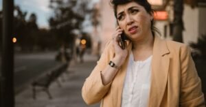 Mulher fala ao celular em calçada de rua urbana com expressão preocupada