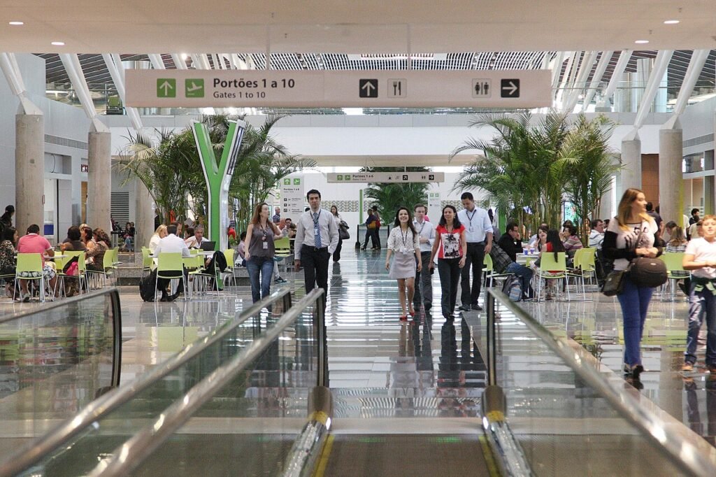 Saguão do Aeroporto Internacional de Brasília com passageiros e placa de portões de embarque