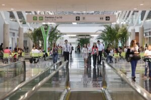 Saguão do Aeroporto Internacional de Brasília com passageiros e placa de portões de embarque
