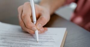 Mão assinando um documento sobre a mesa com caneta esferográfica