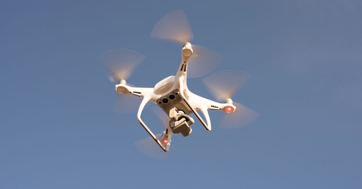 Drone branco em voo contra o céu azul