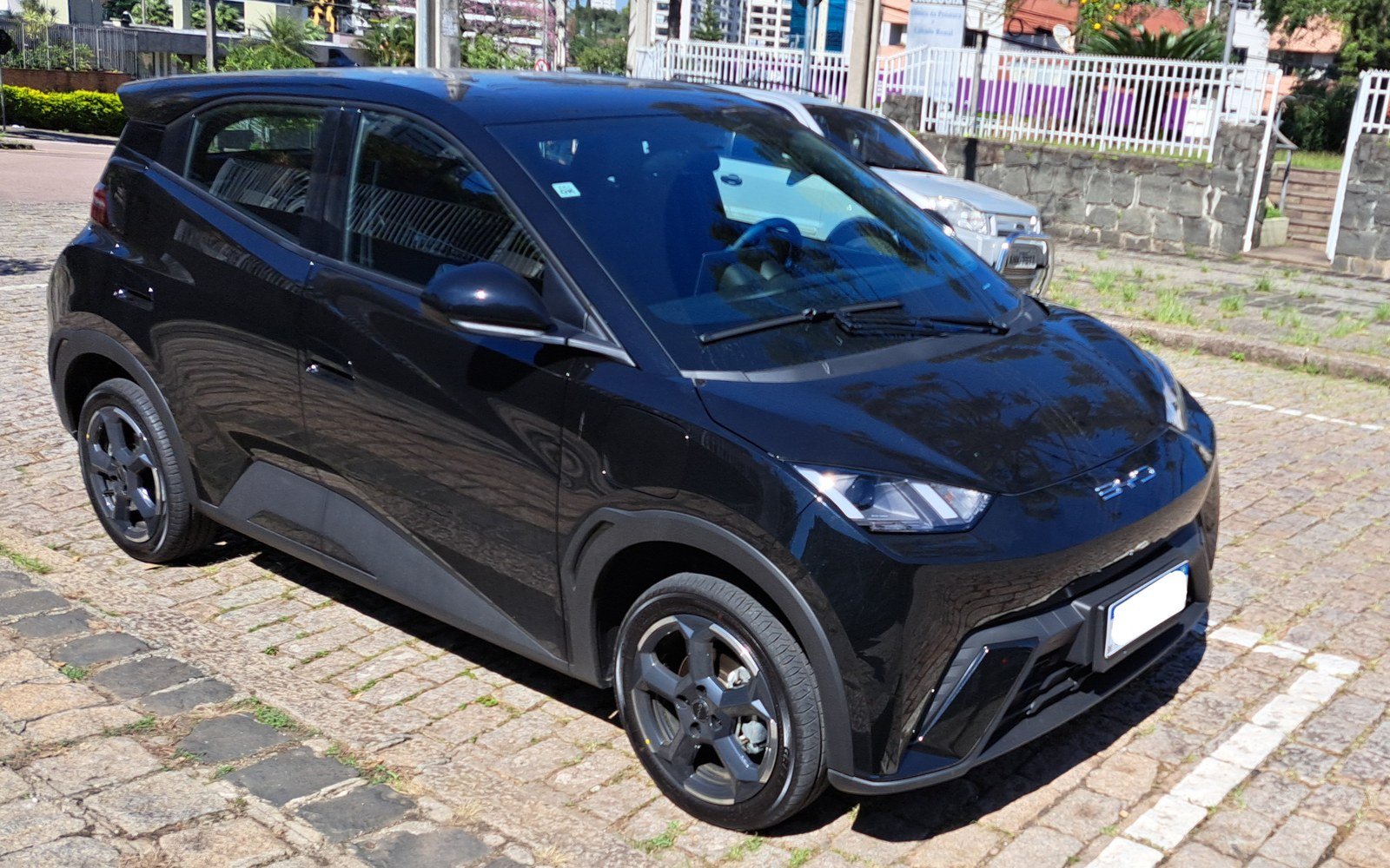 BYD Dolphin Mini preto estacionado em rua de calçamento no Brasil