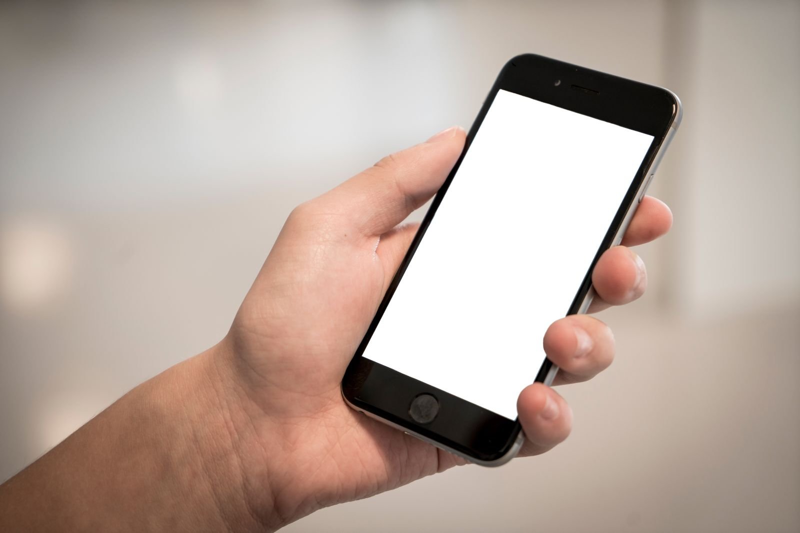 Mão segurando um smartphone preto com a tela em branco