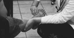 Profissional de saúde examina o pé de um paciente durante consulta em clínica