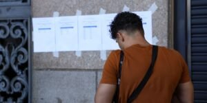 Candidato de costas consulta listas de resultado de concurso afixadas em parede