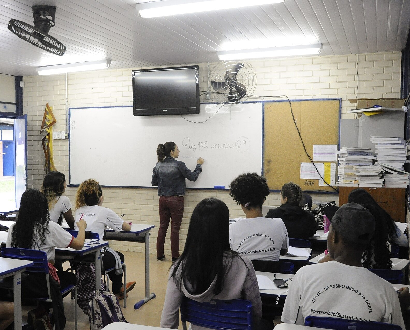 Professora escreve no quadro branco diante de alunos de uniforme em sala de aula do Centro de Ensino Médio da Asa Norte, em Brasília