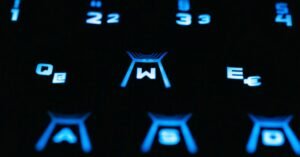 Teclado de computador retroiluminado em azul, com as teclas W, A, S e D em destaque