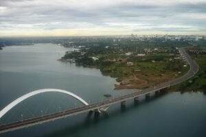 Vista aérea da Ponte Juscelino Kubitschek sobre o Lago Paranoá, com a cidade ao fundo