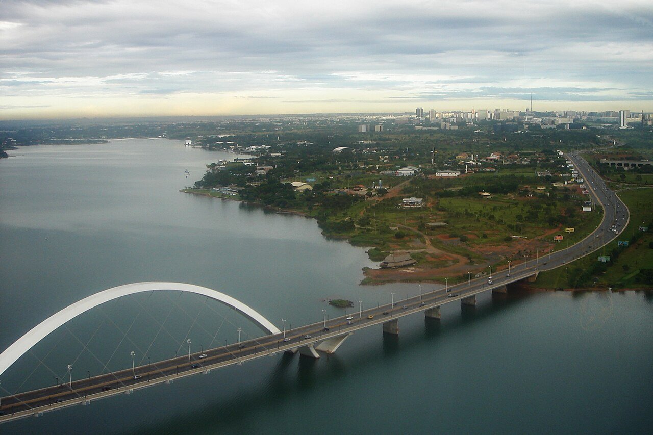 Vista aérea da Ponte Juscelino Kubitschek sobre o Lago Paranoá, com a cidade ao fundo