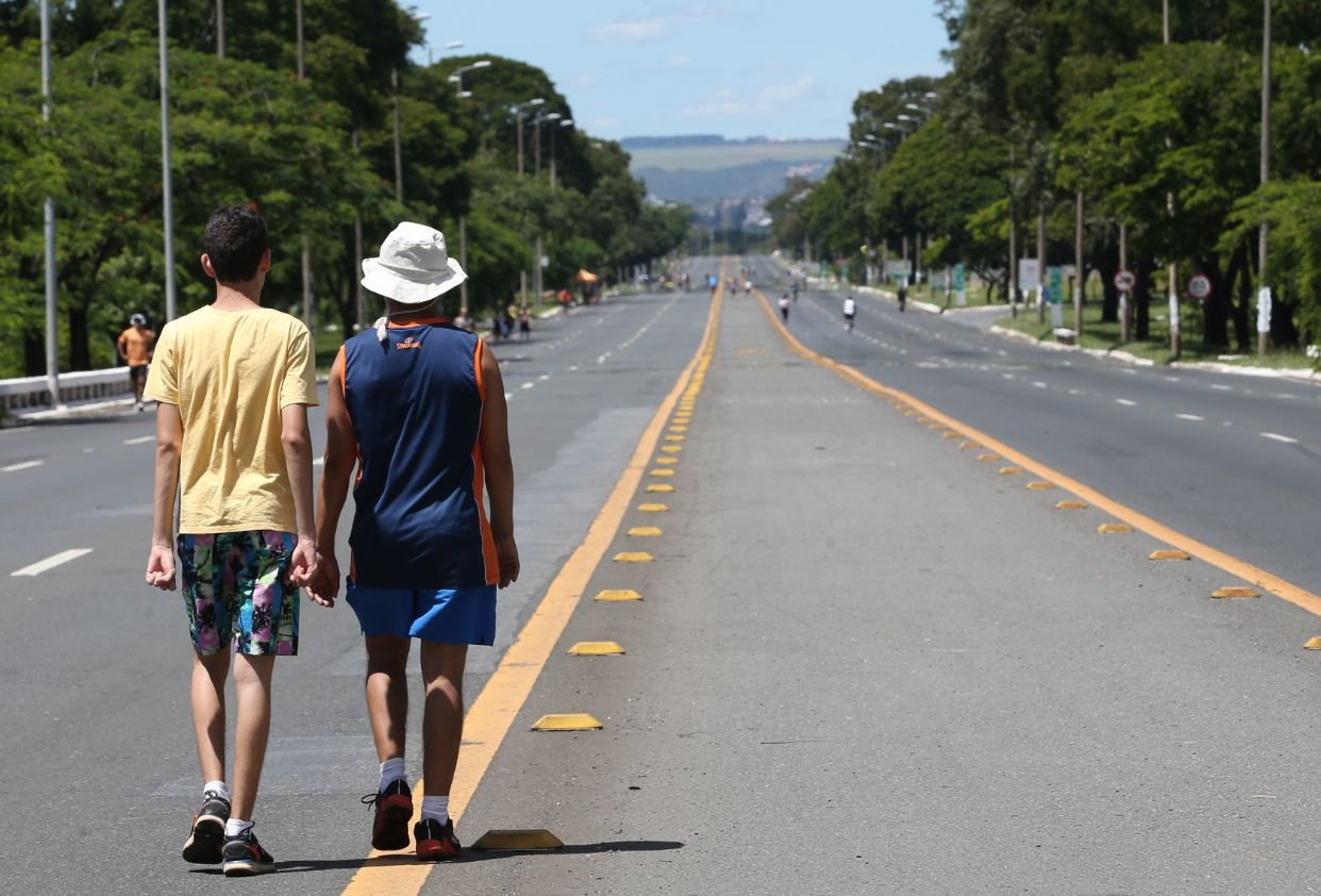 Pista do Eixão do Lazer fechada para carros, com pedestres caminhando pela faixa central em Brasília