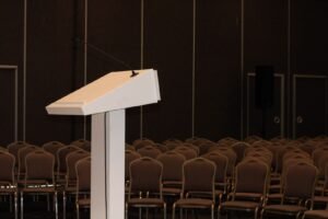 Auditório vazio com púlpito e microfone à frente de fileiras de cadeiras, preparado para evento