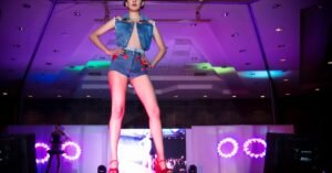 Modelo desfila em passarela iluminada durante apresentação de moda em ambiente fechado