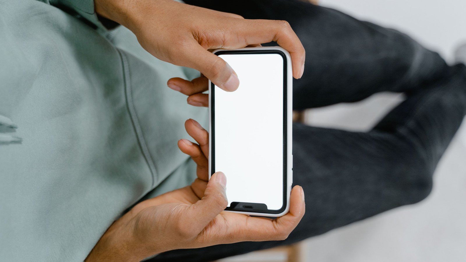 Mãos de uma pessoa segurando um celular com a tela em branco