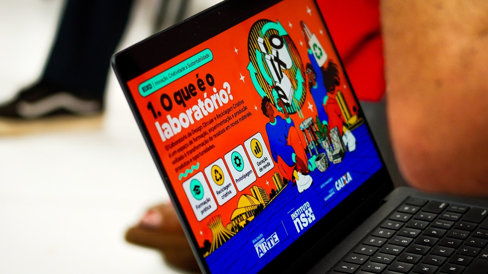 Notebook exibe slide do Laboratório de Design Circular do projeto EIXO, com ilustração colorida e a silhueta de Brasília