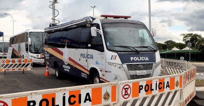 Micro-ônibus da Polícia Militar do DF estacionado atrás de barreiras com a inscrição POLÍCIA
