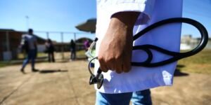 Estudante de medicina de jaleco branco segura estetoscópio na entrada de local de prova
