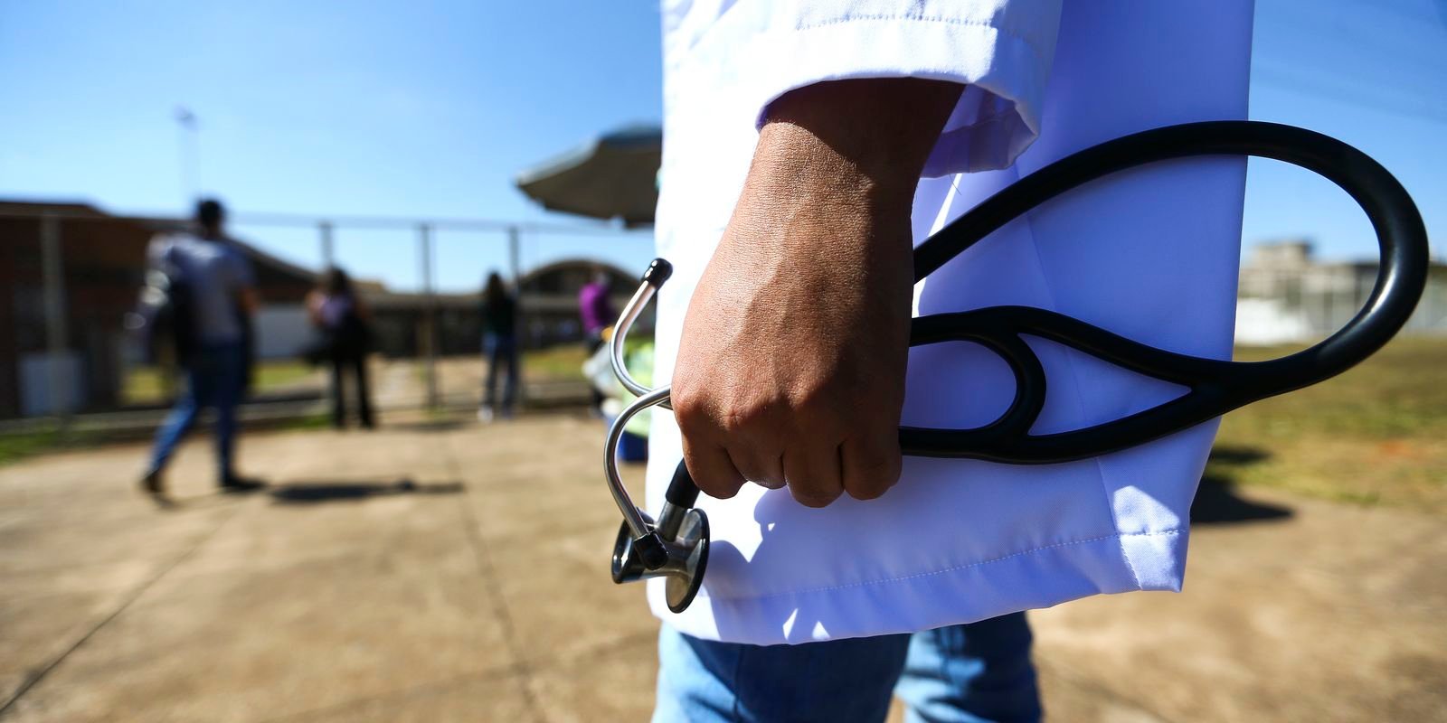 Estudante de medicina de jaleco branco segura estetoscópio na entrada de local de prova