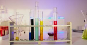 Tubos de ensaio coloridos em suporte sobre bancada de laboratório