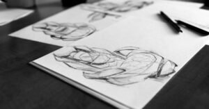 Desenhos a lápis de mãos em cadernos de esboço sobre mesa escura