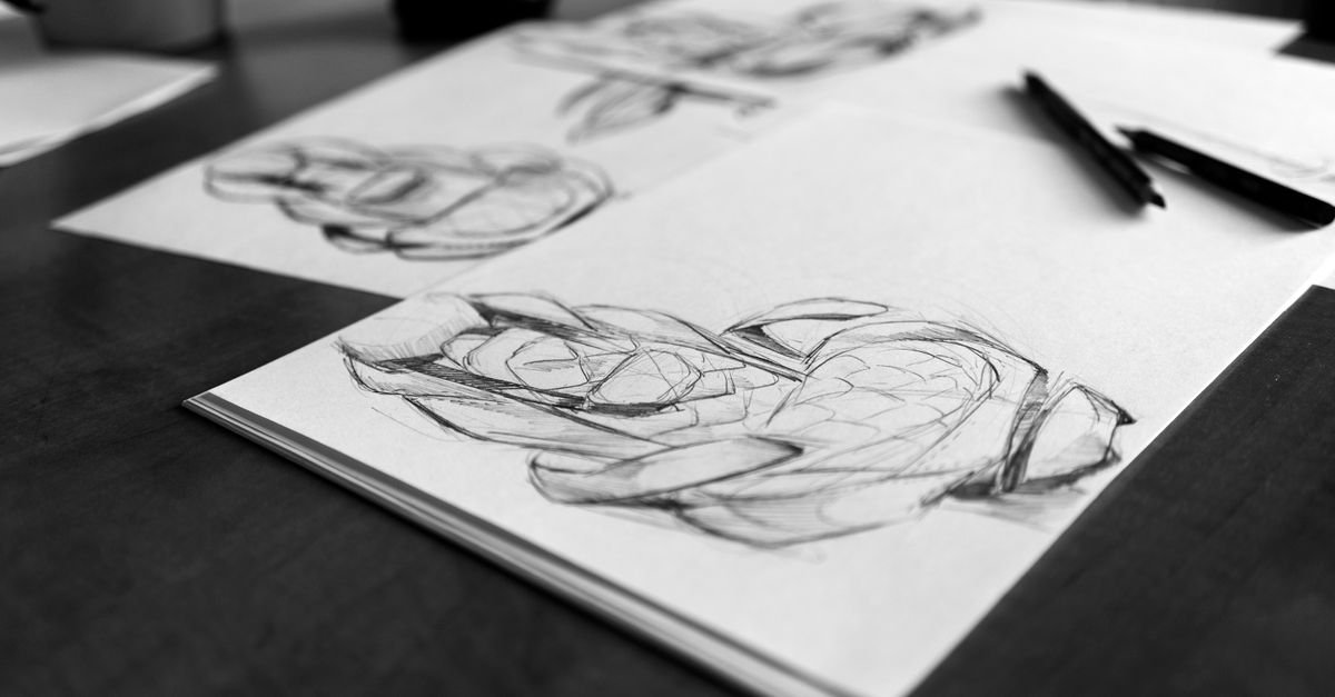 Desenhos a lápis de mãos em cadernos de esboço sobre mesa escura