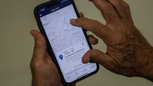 Mãos de eleitor seguram celular com a tela do aplicativo e-Título na função Onde votar