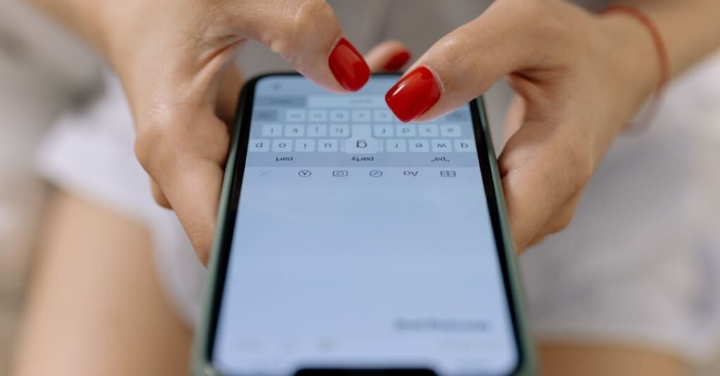 Close de mãos digitando mensagem na tela de um celular